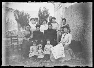 Groupe de femmes et petites filles posant autour d'une femme tenant un ouvrage de broderie. / [Martial Aubrespy, photographe amateur].