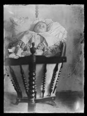 Marie-Louise Aubrespy bébé allongée dans son berceau en bois. / [Martial Aubrespy, photographe amateur].