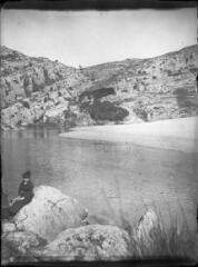 1 vue  - Femme assise sur un rocher devant une étendue d\'eau. / [Anonyme] (ouvre la visionneuse)
