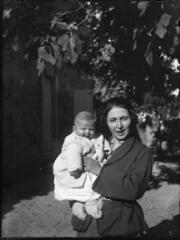 1 vue  - Femme avec son bébé dans les bras dans un jardin. / [Anonyme] (ouvre la visionneuse)