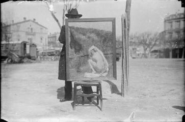 1 vue  - Toile peinte représentant une jeune femme nue posée sur une chaise par un homme sur la place d\'un village. / [Anonyme] (ouvre la visionneuse)