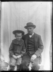 1 vue Portrait d'homme et d'enfant assis devant une bâche blanche. / [Anonyme]