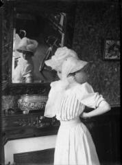 1 vue  - Jeune femme vêtue de blanc se regardant dans une glace. / [Anonyme] (ouvre la visionneuse)
