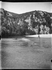 1 vue Homme marchant dans un cours d'eau et paysage rocheux. / [Anonyme]