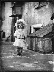 1 vue  - Portrait d\'une fillette en robe et chapeau blancs, dans une cour. / [Anonyme] (ouvre la visionneuse)