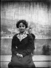 1 vue  - Portrait de jeune femme assise, un enfant se tenant à l\'arrière plan derrière elle. / [Anonyme] (ouvre la visionneuse)