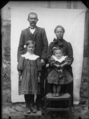 1 vue  - Portrait de la famille du lieu-dit Escande (?) : couple derrière deux petites filles dont l\'une est debout sur une chaise. / [SAUNAL, Léon (photographe)] (ouvre la visionneuse)