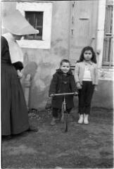 1 vue Deux enfants devant une maison, dont un petit garçon sur un vélo. / [SAUNAL, Léon (photographe)]